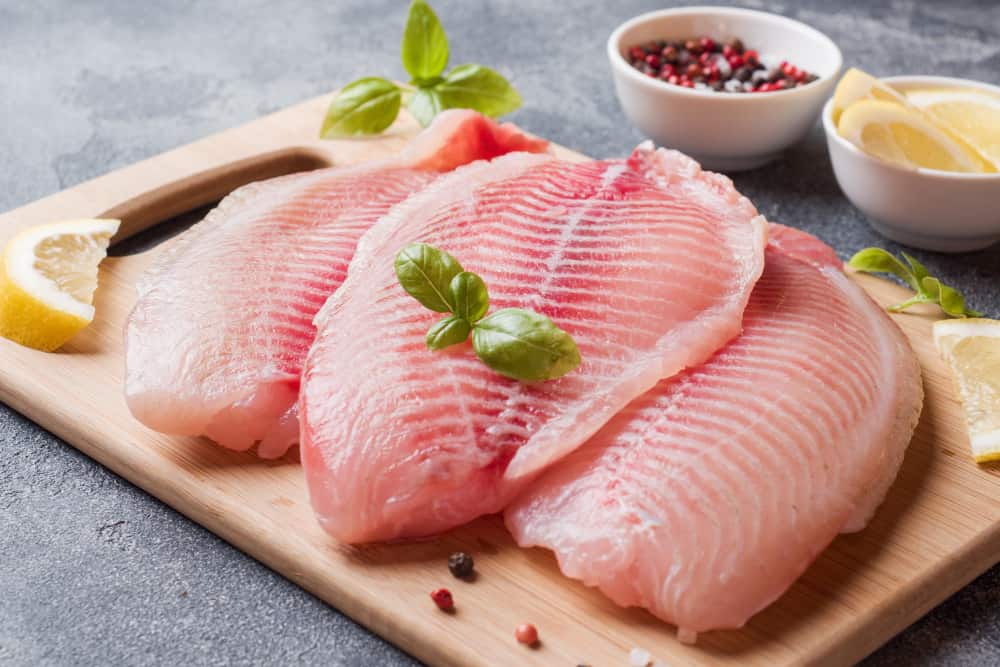 raw-fish-fillet-tilapia-cutting-board-with-lemon-spices-dark-table